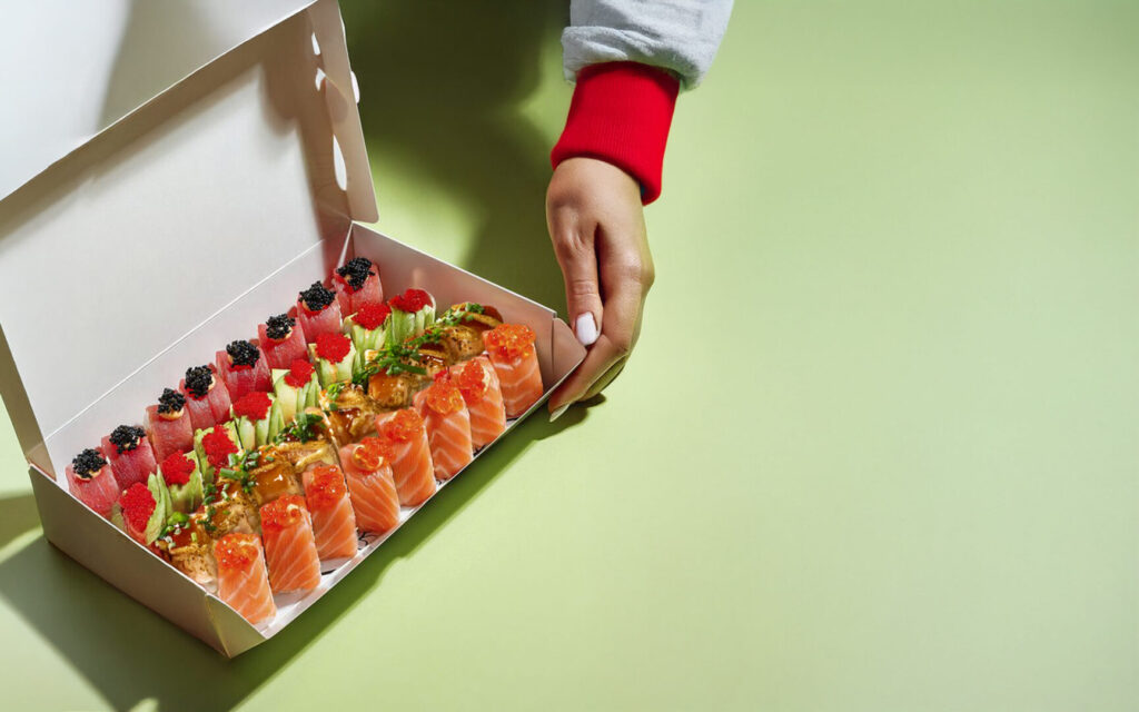 Plateau du mois à emporter Tastyrice avec assortiment de sushis premium ornés de fruits et sauces, dans box ouverte. - Sushi Paris - Sushi Bordeaux - box sushis