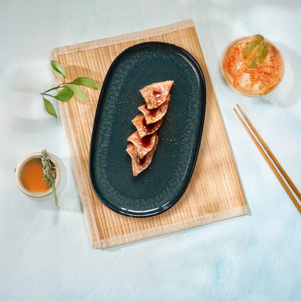 Tranches de tataki de saumon légèrement grillé Tastyrice, assaisonnées et servies sur assiette noire. - Sushi Paris - Sushi Bordeaux - Sashimis - Tatakis